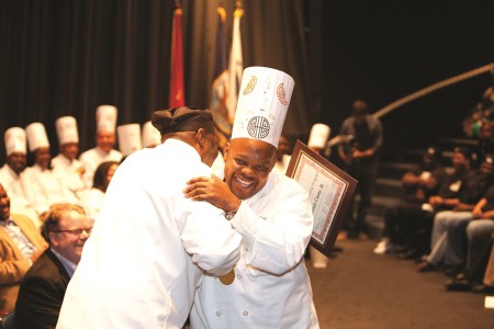 Louis, a 2012 graduate of the Culinary Job Training program, accepts his certificate and embraces an instructor on graduation day.